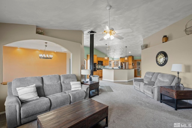 carpeted living room featuring ceiling fan with notable chandelier and vaulted ceiling