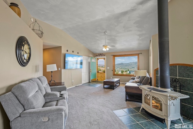 living room with a wood stove, carpet flooring, lofted ceiling, and ceiling fan