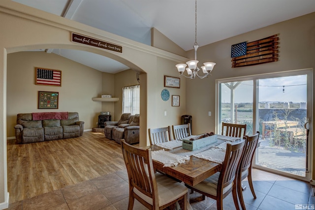 dining room with lofted ceiling, a wealth of natural light, a wood stove, and a chandelier