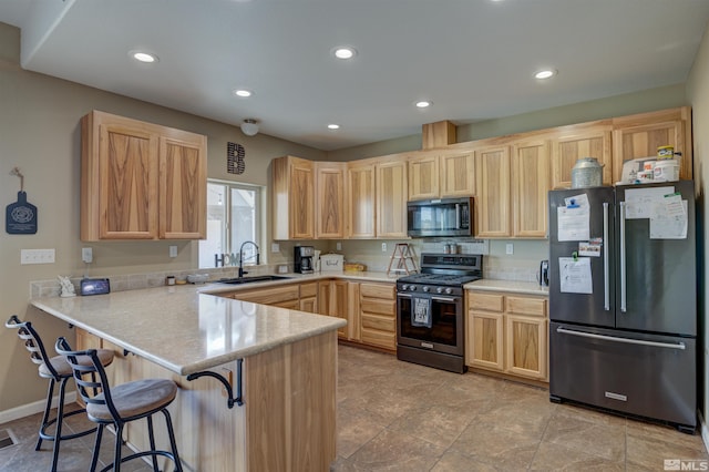 kitchen with gas range, kitchen peninsula, sink, fridge, and light brown cabinets