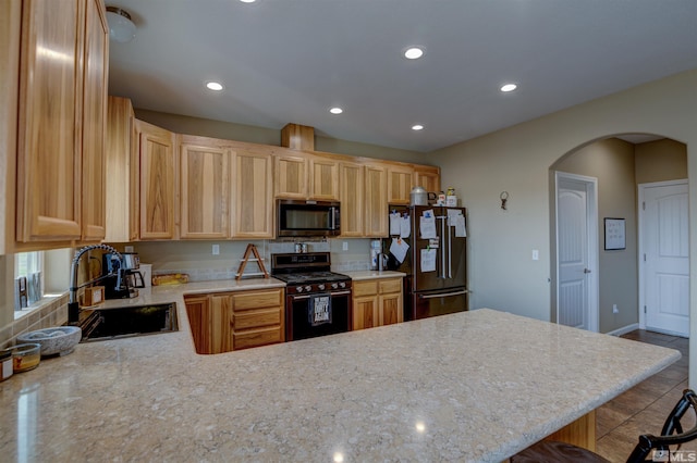 kitchen with kitchen peninsula, high end refrigerator, a breakfast bar, and black gas range