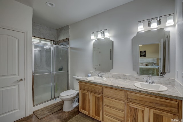 bathroom featuring toilet, a shower with shower door, and vanity