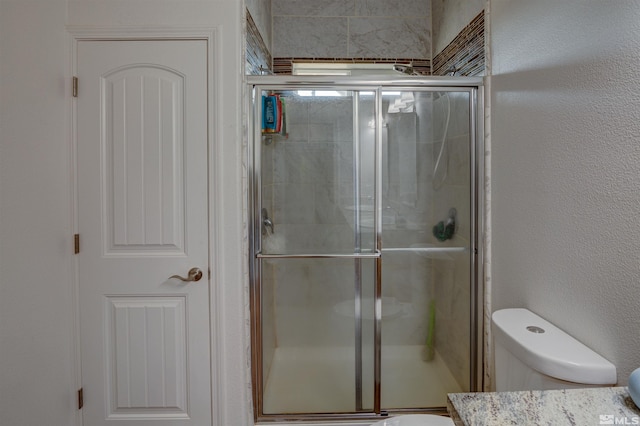 bathroom with vanity, a shower with shower door, and toilet