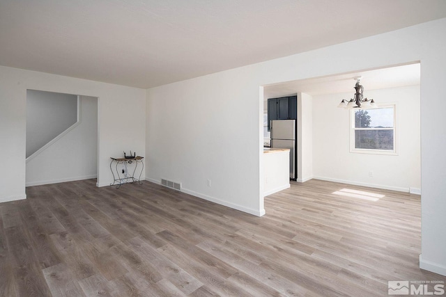 empty room featuring an inviting chandelier and hardwood / wood-style flooring