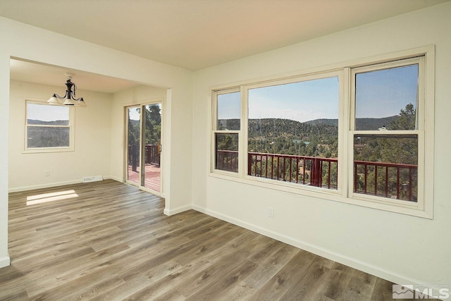 unfurnished room featuring hardwood / wood-style floors, a mountain view, and a chandelier