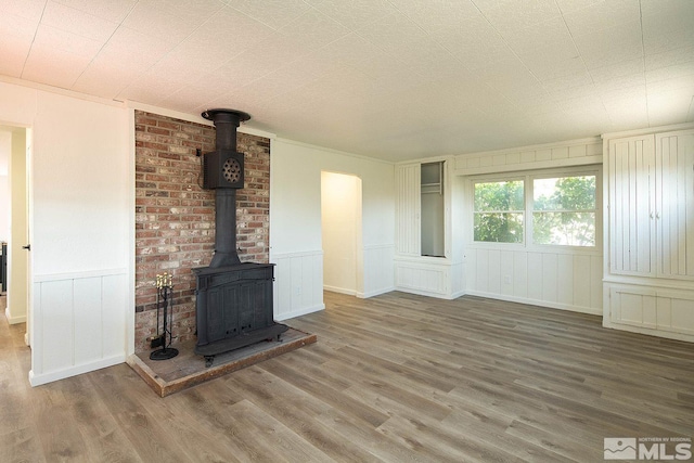 unfurnished living room with wood-type flooring and a wood stove