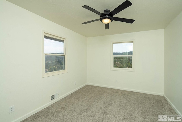 carpeted spare room with a wealth of natural light and ceiling fan