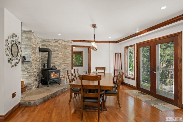 dining area featuring crown molding, wood-type flooring, french doors, and a wood stove