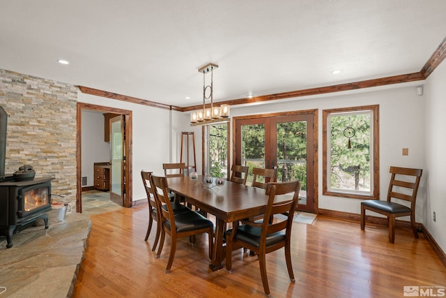 dining space with light hardwood / wood-style flooring, ornamental molding, french doors, and a wood stove