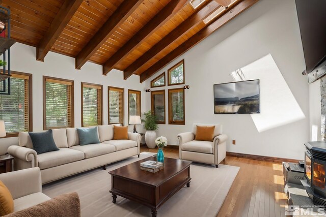 living room featuring a skylight, a wood stove, beam ceiling, light wood-type flooring, and high vaulted ceiling