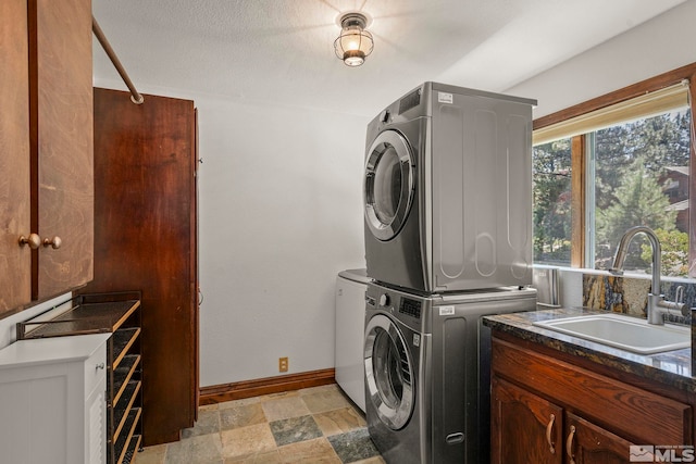 clothes washing area with stacked washer / drying machine and sink