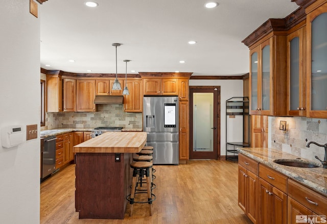 kitchen with sink, stainless steel appliances, a center island, wood counters, and light wood-type flooring