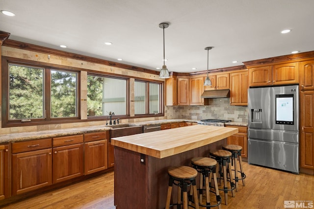 kitchen featuring a kitchen island, butcher block countertops, hanging light fixtures, light hardwood / wood-style floors, and stainless steel appliances