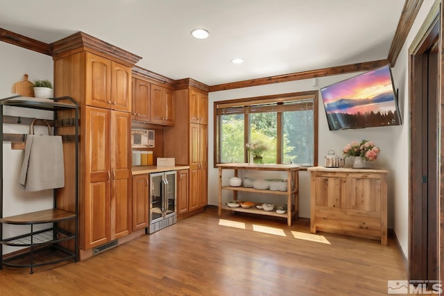 kitchen with wine cooler, ornamental molding, and light wood-type flooring