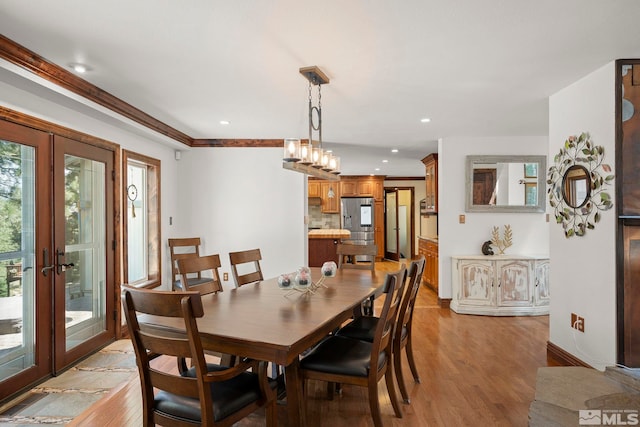 dining room with french doors, crown molding, and light hardwood / wood-style flooring