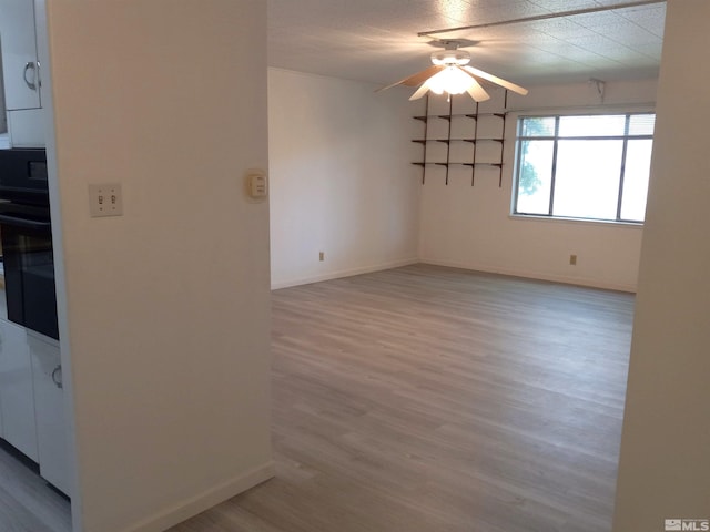 empty room with ceiling fan and light hardwood / wood-style flooring