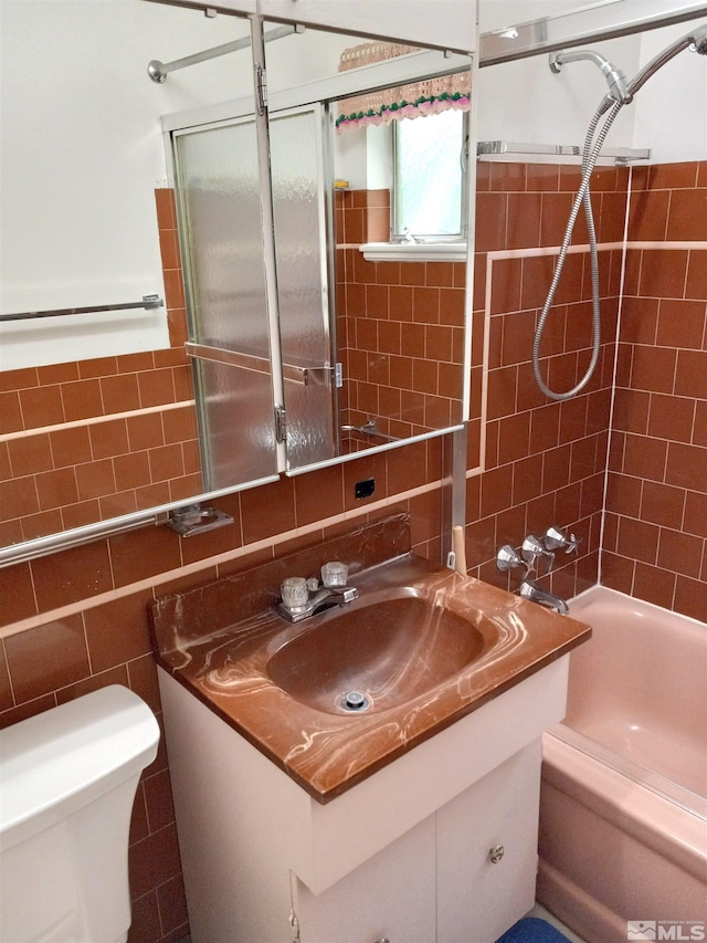 full bathroom with tiled shower / bath, vanity, toilet, and tile walls