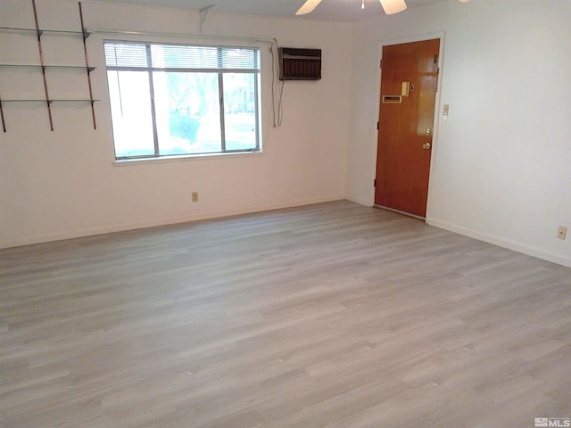 spare room featuring light hardwood / wood-style floors, an AC wall unit, and ceiling fan