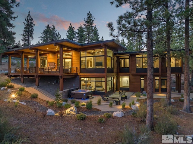 back house at dusk featuring a patio area