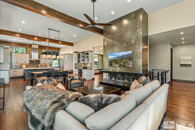 living room featuring hardwood / wood-style floors, beam ceiling, a high end fireplace, and ceiling fan