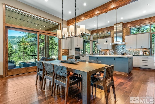 dining room with hardwood / wood-style flooring, a notable chandelier, and beamed ceiling