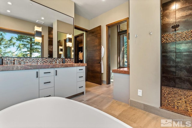 bathroom with vanity, separate shower and tub, and decorative backsplash