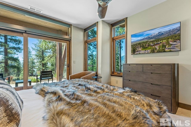 carpeted bedroom with multiple windows, access to exterior, and ceiling fan