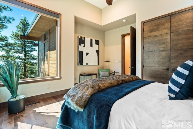 bedroom with dark wood-type flooring, ceiling fan, and a closet