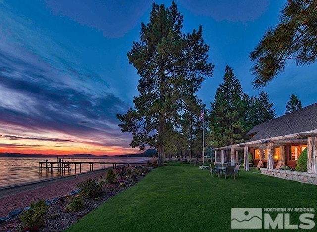 yard at dusk featuring a water view