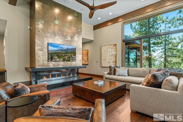 living room with a tiled fireplace, hardwood / wood-style flooring, a wealth of natural light, and ceiling fan