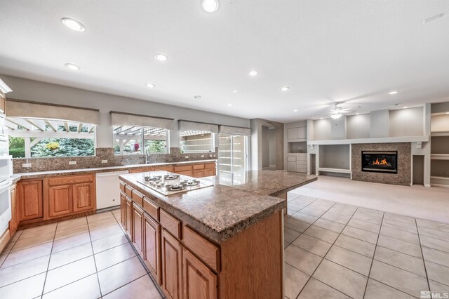 kitchen with tasteful backsplash, white appliances, built in features, a kitchen island, and light tile patterned floors