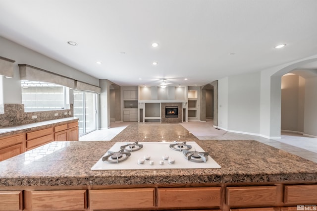 kitchen with white gas cooktop, light stone countertops, tasteful backsplash, and light tile patterned floors