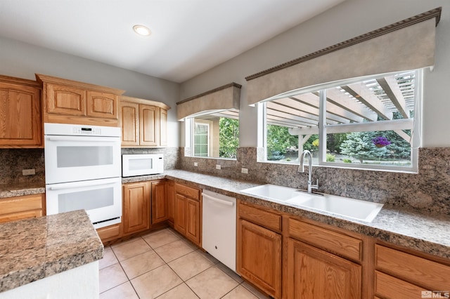 kitchen featuring tasteful backsplash, sink, light tile patterned floors, and white appliances