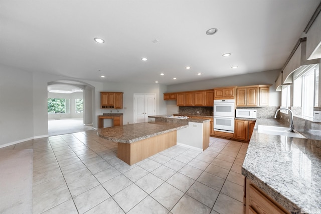 kitchen featuring sink, white appliances, light tile patterned flooring, and a kitchen island
