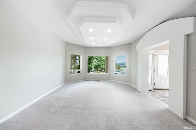 unfurnished living room with built in shelves, light colored carpet, and ceiling fan