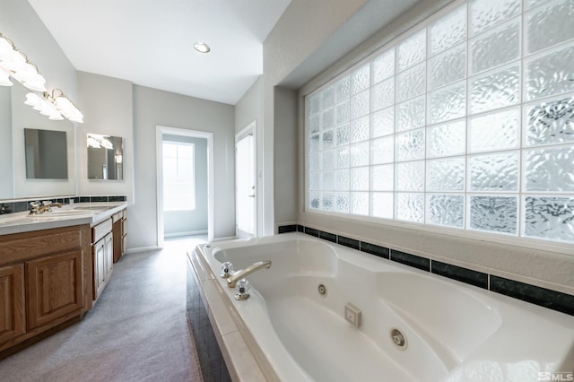 bathroom featuring tiled tub and vanity