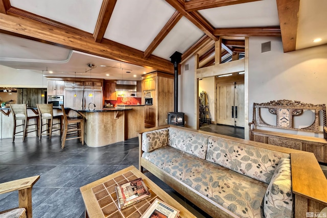 tiled living room with sink, a wood stove, and lofted ceiling with beams