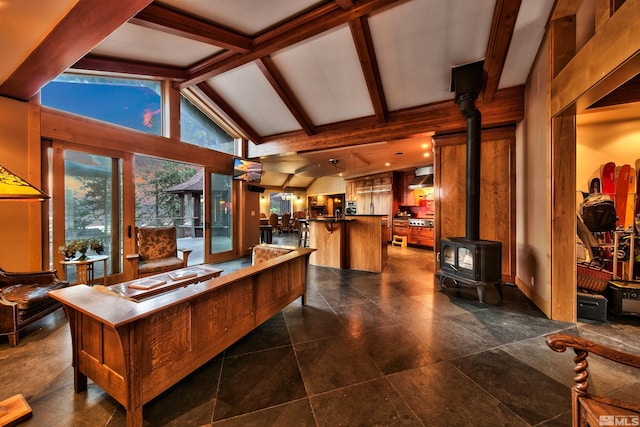 living room featuring vaulted ceiling with beams, dark tile patterned floors, and a wood stove