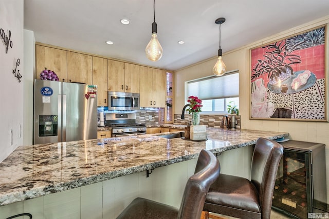 kitchen featuring decorative light fixtures, light brown cabinetry, stainless steel appliances, stone countertops, and kitchen peninsula