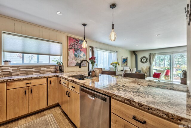 kitchen with pendant lighting, light wood-type flooring, sink, dishwasher, and light stone counters