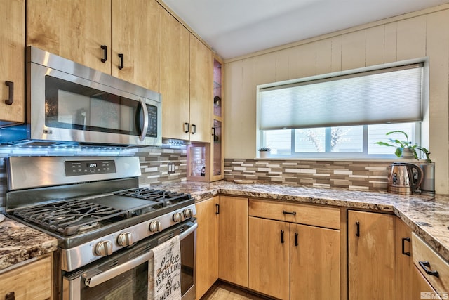 kitchen featuring light stone counters, decorative backsplash, and appliances with stainless steel finishes