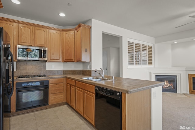 kitchen featuring black appliances, kitchen peninsula, tile countertops, and sink