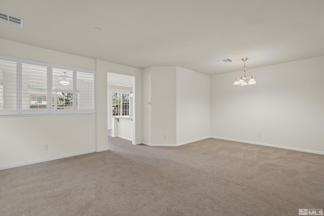 carpeted spare room with a notable chandelier