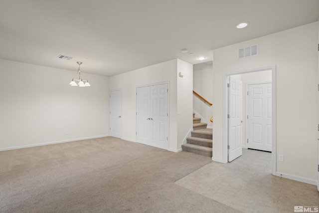 empty room with light carpet and a chandelier