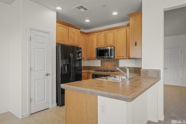 kitchen with kitchen peninsula, appliances with stainless steel finishes, tile countertops, and tasteful backsplash