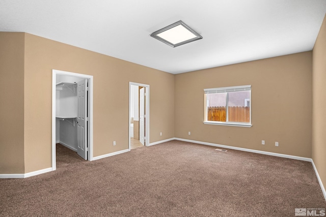 unfurnished bedroom with a spacious closet, carpet floors, a closet, and ensuite bathroom