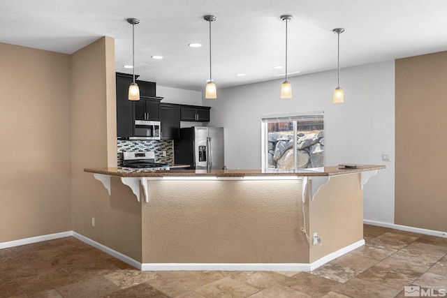 kitchen with stainless steel appliances, a kitchen bar, kitchen peninsula, and backsplash