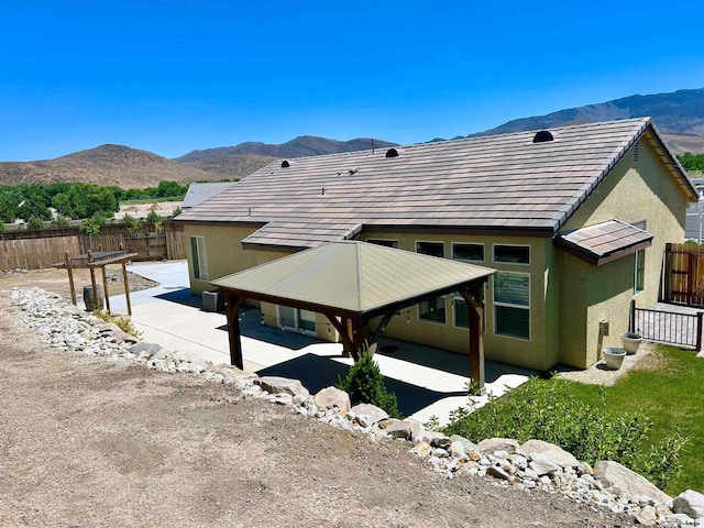 back of property featuring a mountain view and a patio