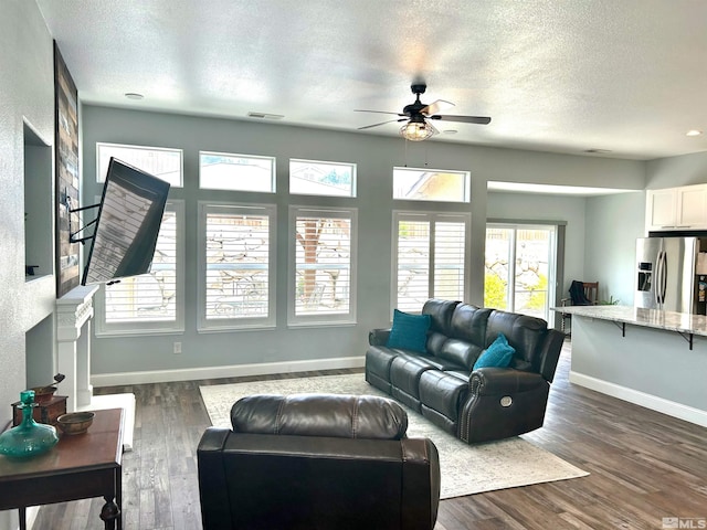 living room with a textured ceiling, dark hardwood / wood-style flooring, and ceiling fan