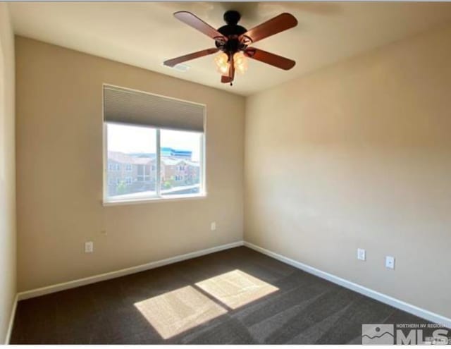 spare room featuring dark carpet and ceiling fan